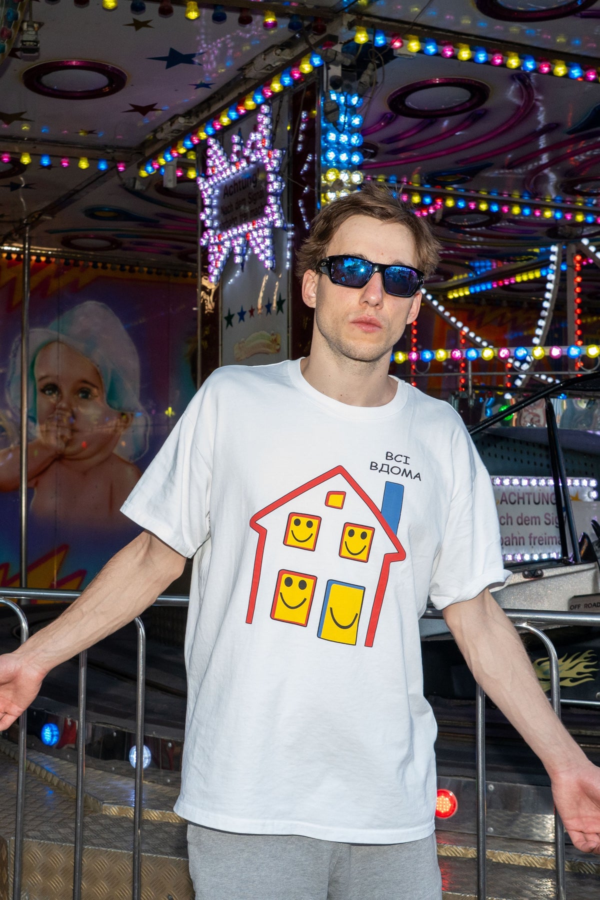 Man wearing the white Everyone’s Home T-shirt with its illustrated print