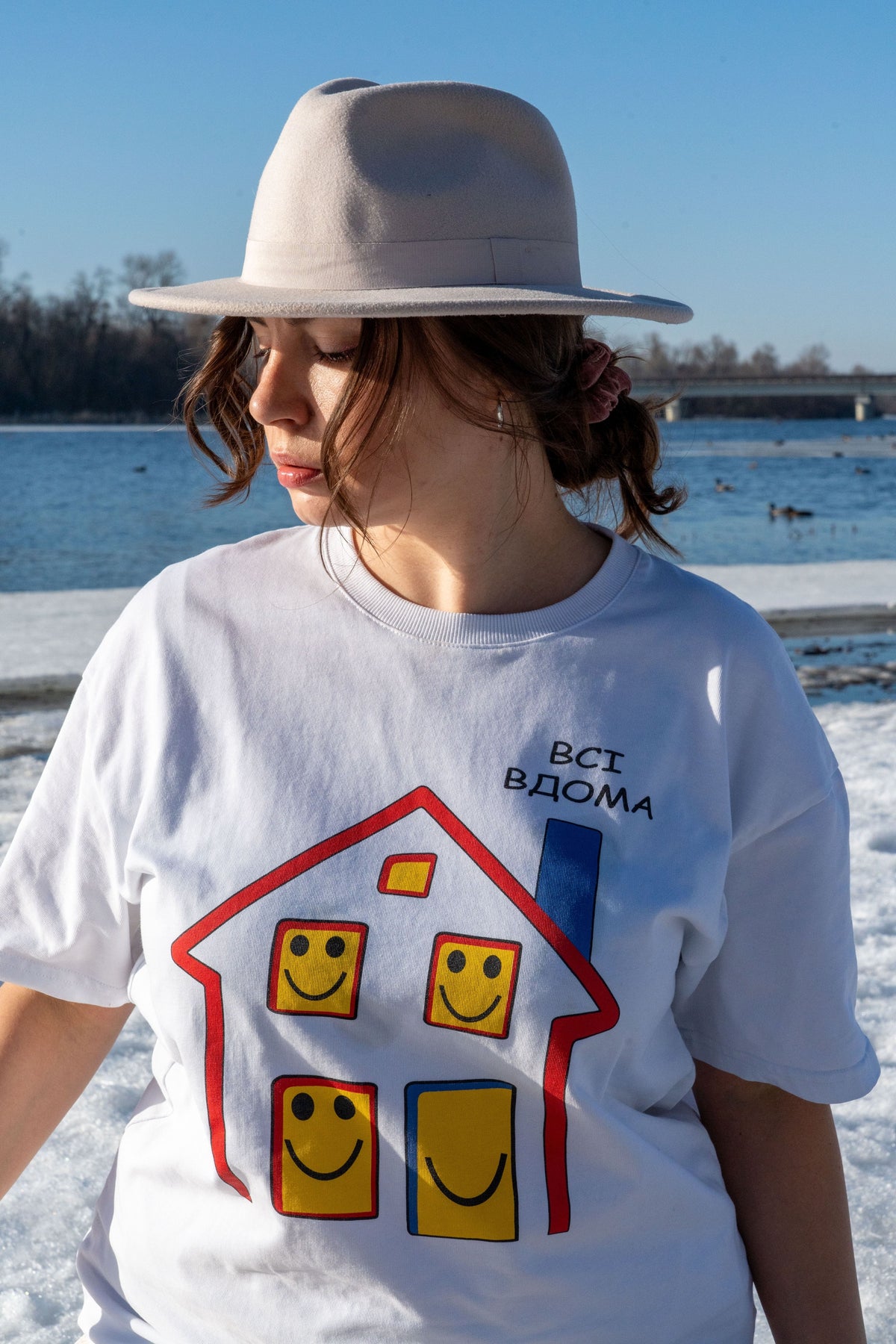 Woman wearing the white Everyone’s Home T-shirt with its illustrated print